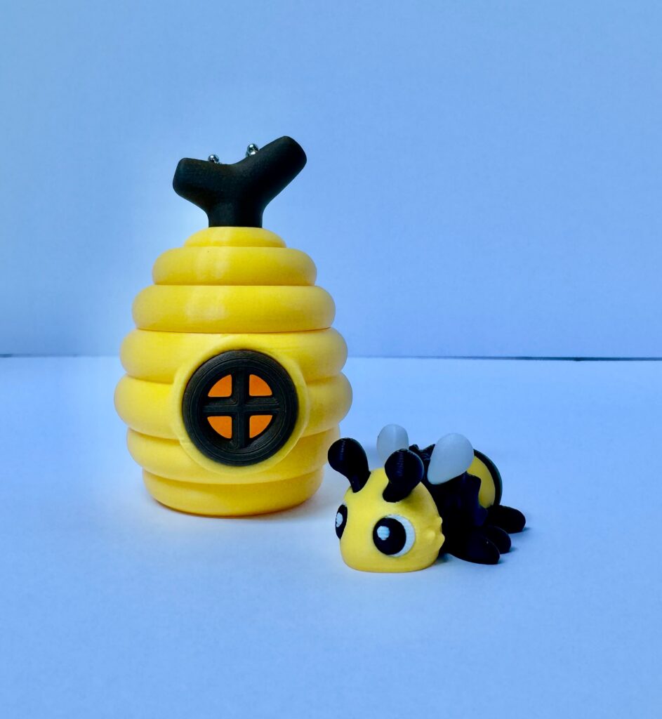Bee Buddy and a yellow hive, photographed against a blue background.